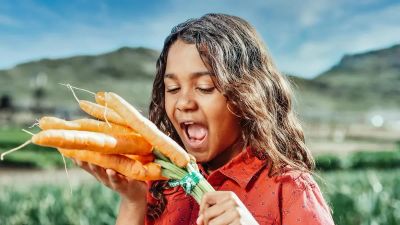 Dziecko z dumą trzyma zebrane marchewki